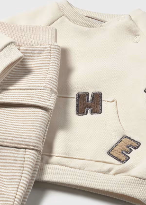 Beige baby boy sporty two-piece set with elastic waist pants and long sleeve sweatshirt with decorative prints and front pocket.